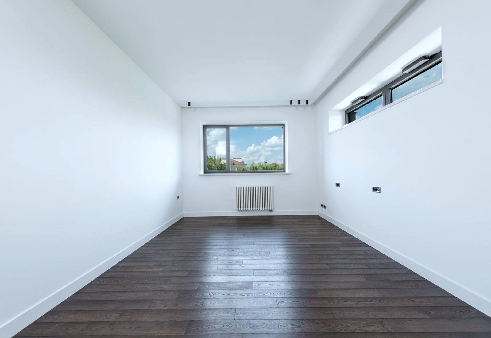 Empty unfurnished room with white walls and a dark wood floor